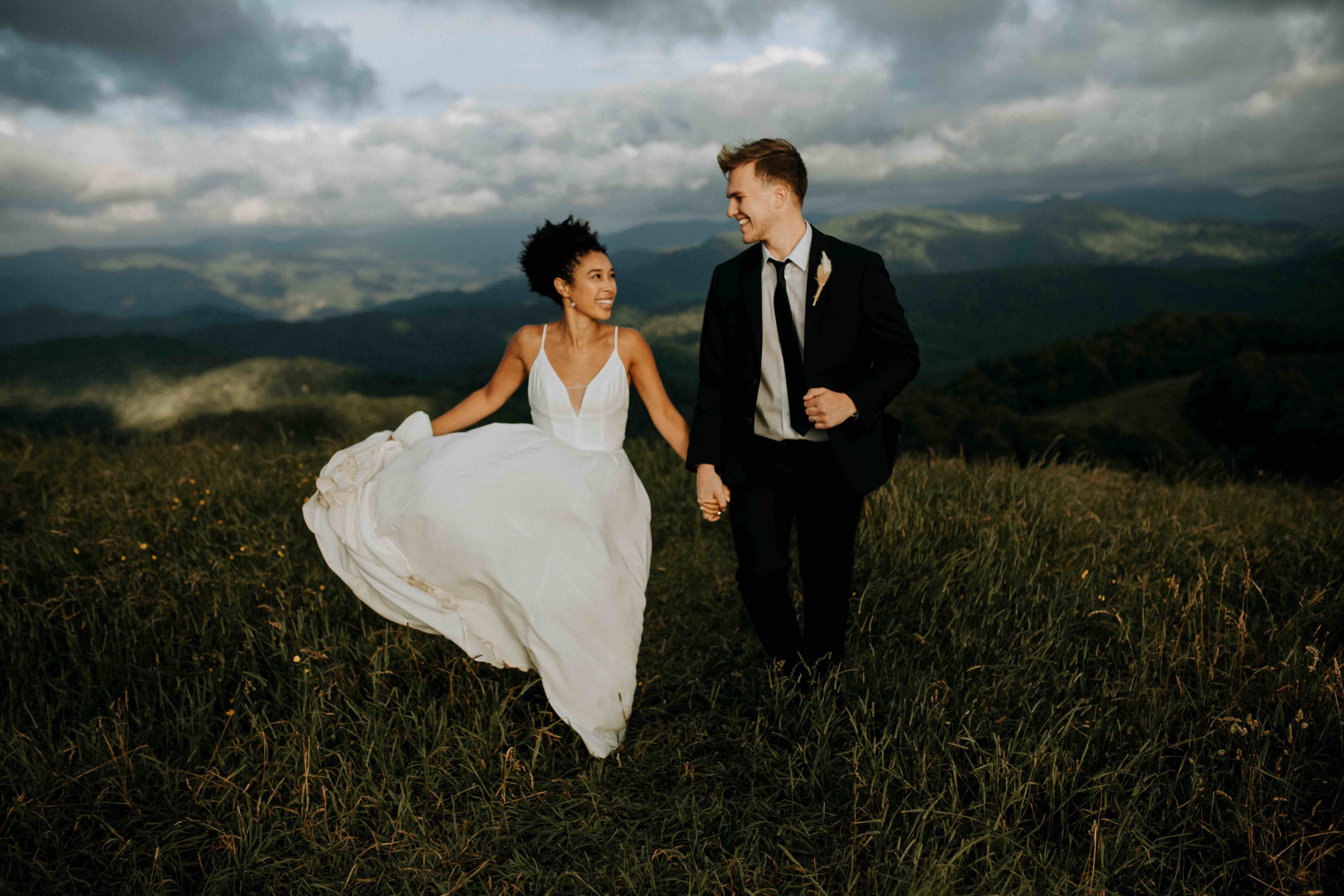 Breanna and Dalton running on a mountain top in their wedding clothes