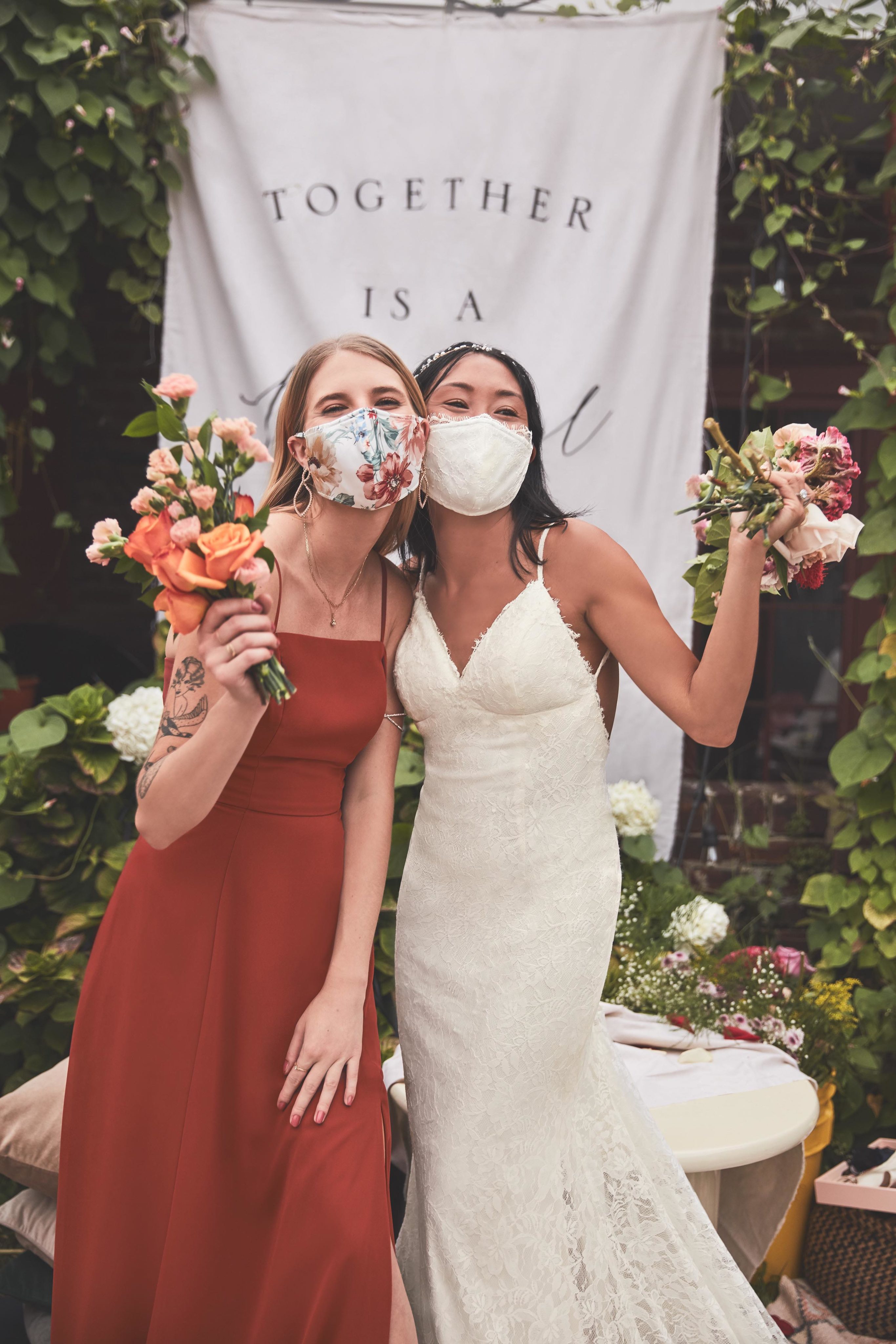 Bride and Bridesmaid wearing facemasks and holding flower bouquets.