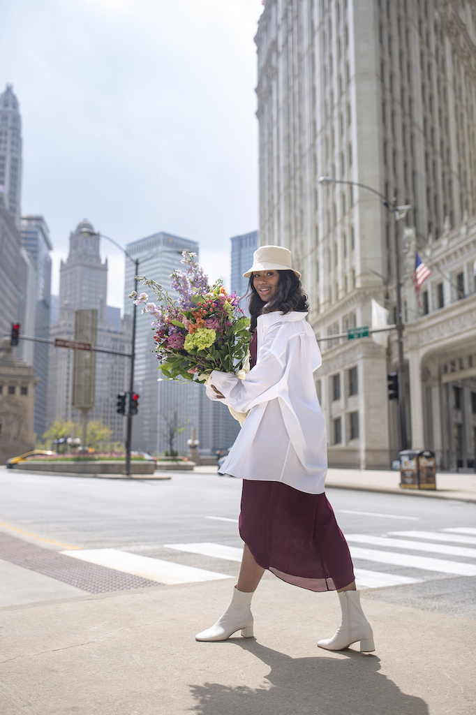 girl walking downtown holding flowers in bridesmaids dress with white dress shirt as a way to restyle a wedding day look