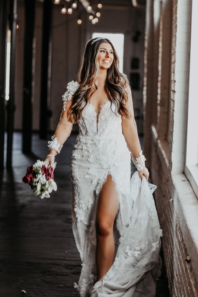 Bride walking wearing a sexy galina signature with illusion long sleeves and a leg slit