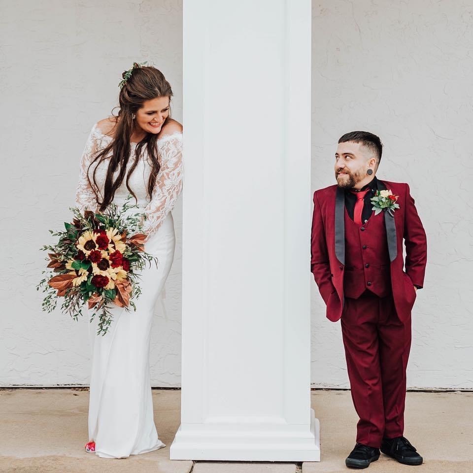 Bride and groom looking at each other on opposite sides of a pillar