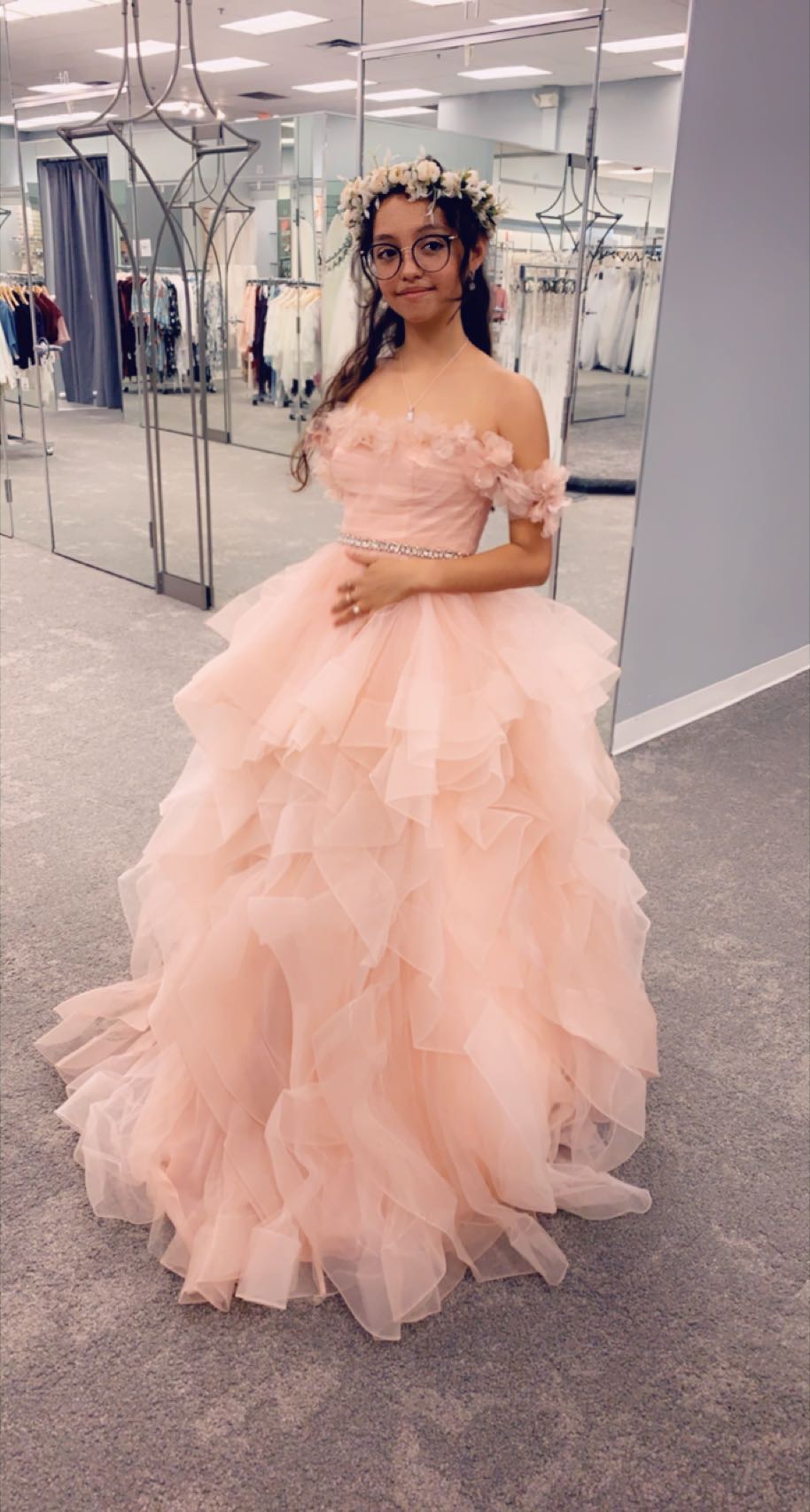 Teenage girl trying on a pink quinceañera dress and flower crown