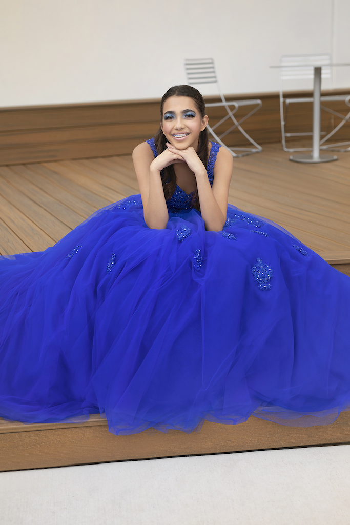 Teenage girl sitting in cobalt blue quinceañera dress