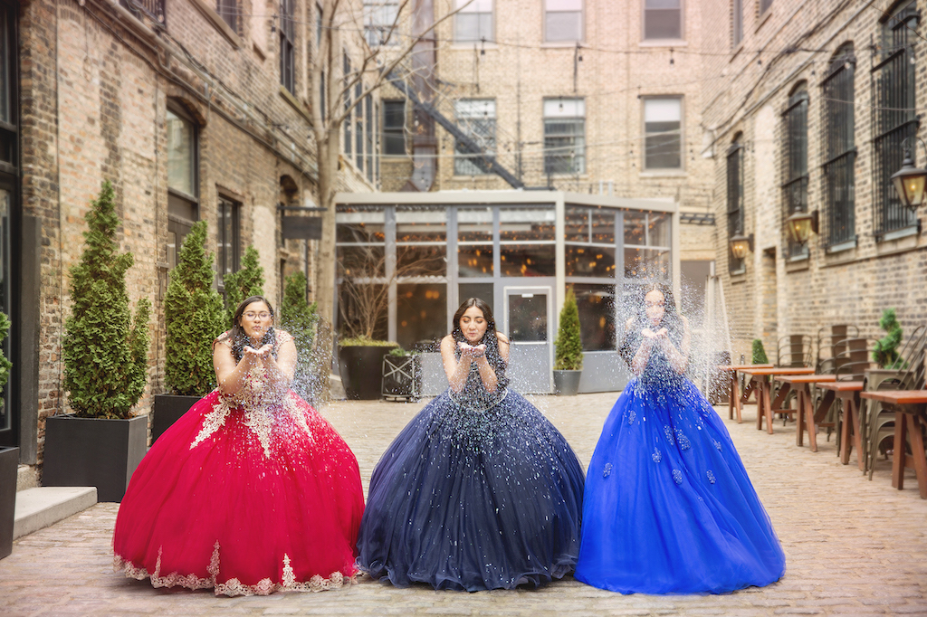 Three teenage girls wearing red, navy, and colbalt quinceañera dresses 