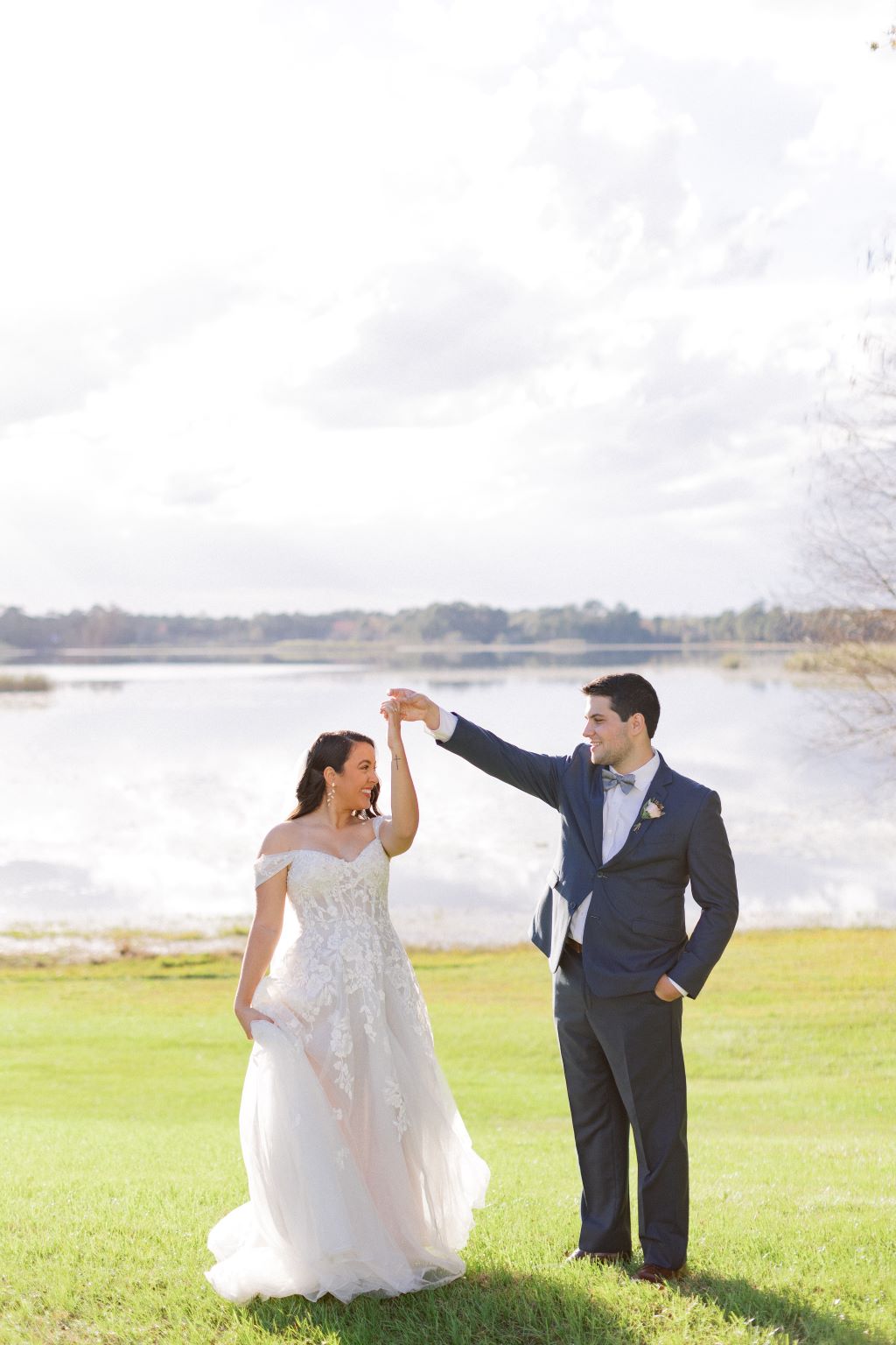 groom twirling bride in front of the water