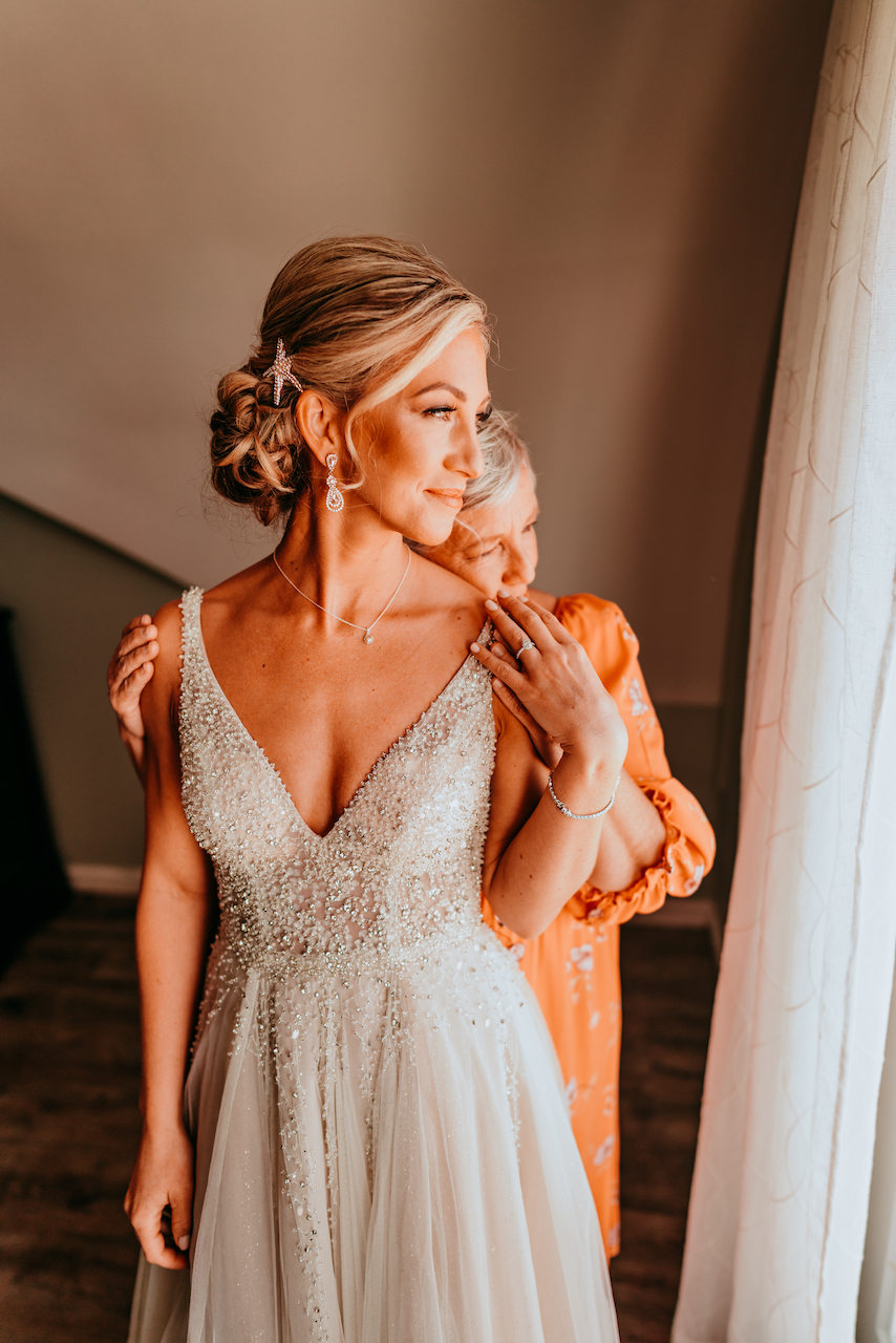 bride in sparkling dress with mother of the bride at the romantic beach wedding in Alabama