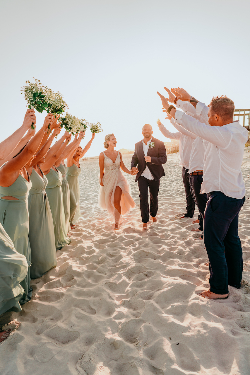bride and groom at their romantic beach wedding in Alabama surrounded by the wedding party