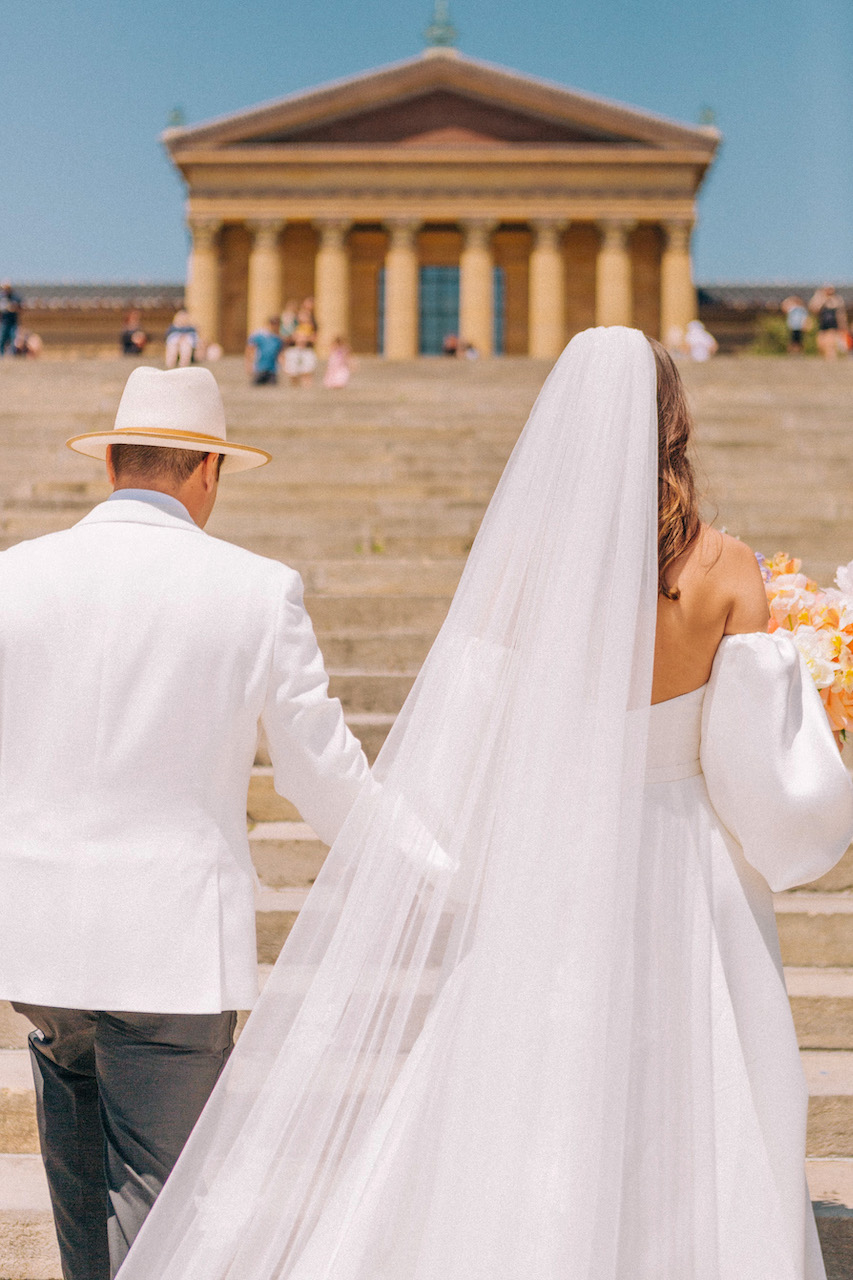 bride and groom walking up steps of philadelphia art museum 