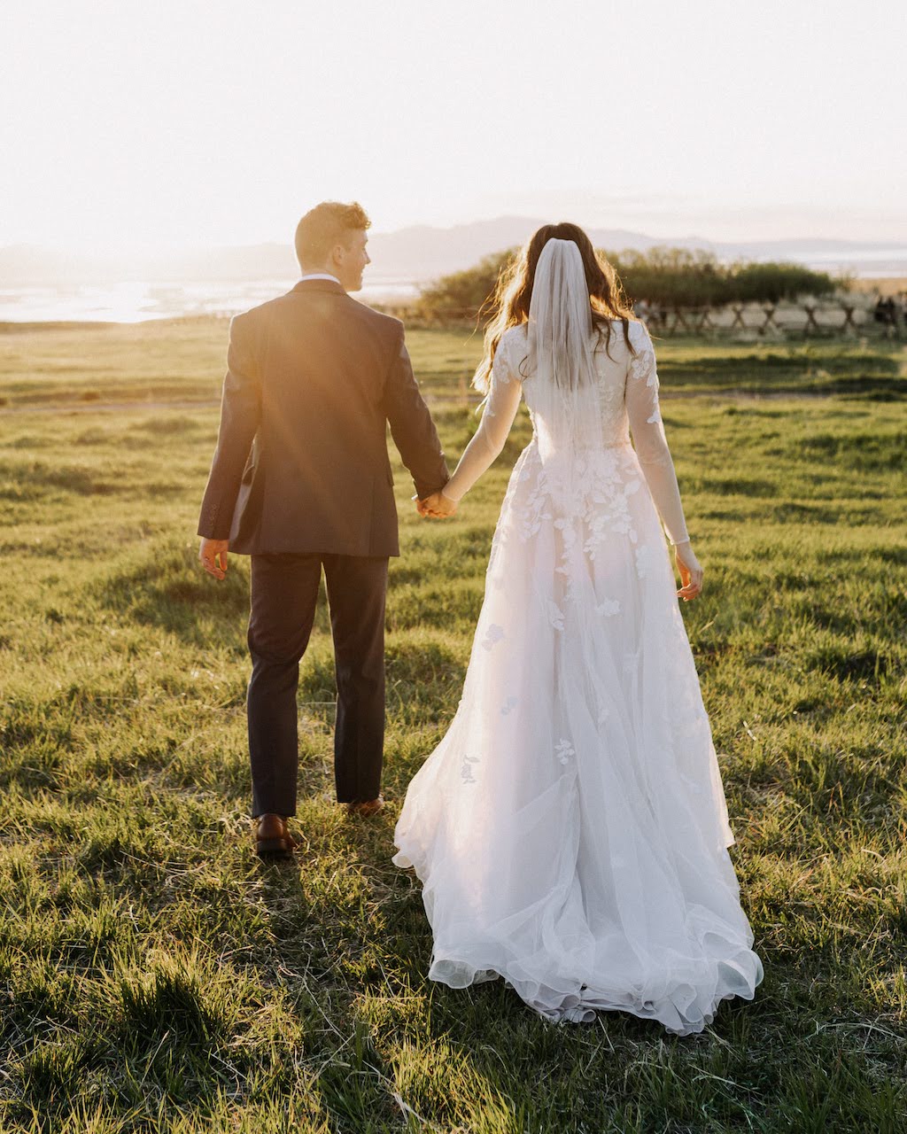 bride and groom walking hand in hand at classic rustic wedding