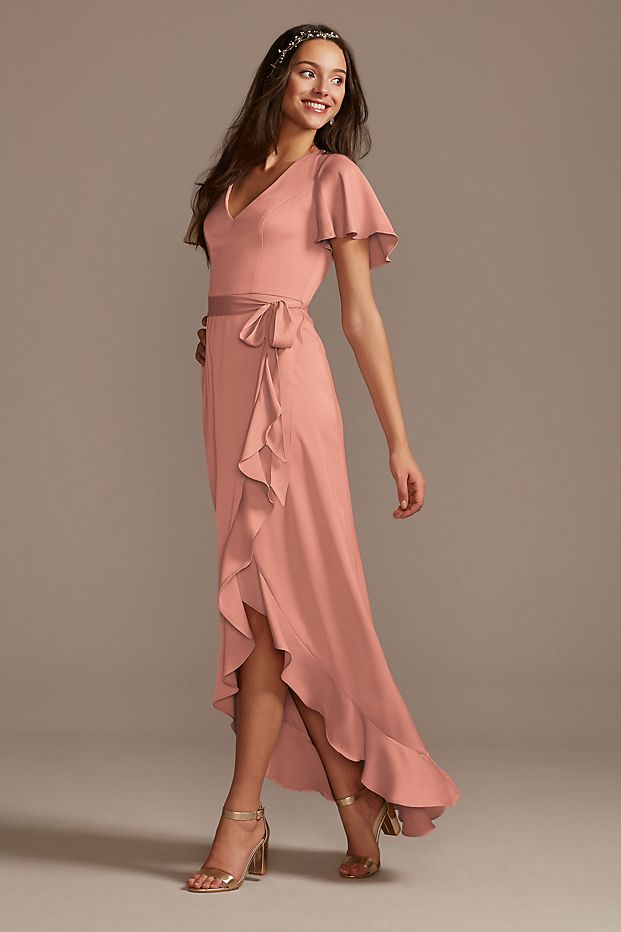 women in desert coral satin dress with ruffle hem and a flattering tie at the waist 