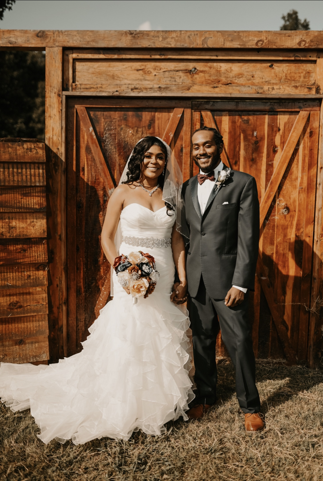 bride and groom in front of barn door at their simple and elegant fall wedding