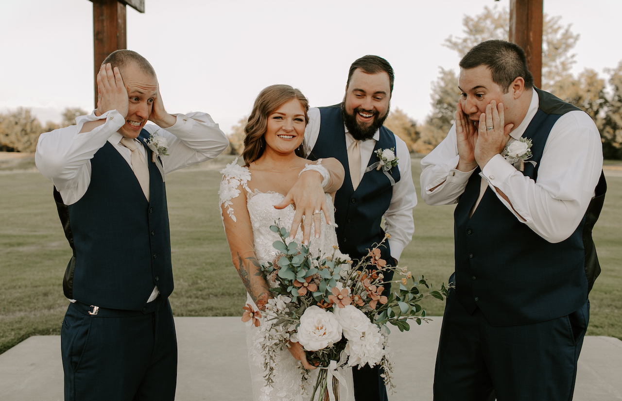 bride showing off ring to groomsmen