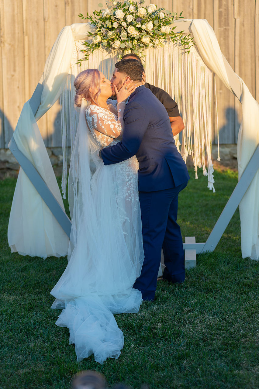Bride and groom kissing at rustic outdoor wedding in Delaware
