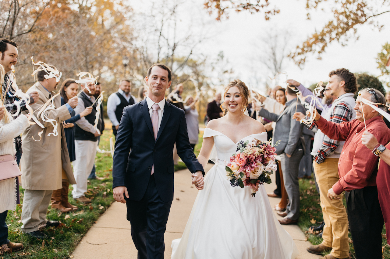 Les mariés se promènent dans une file d'amis et de famille lors d'un mariage romantique en Caroline du Nord