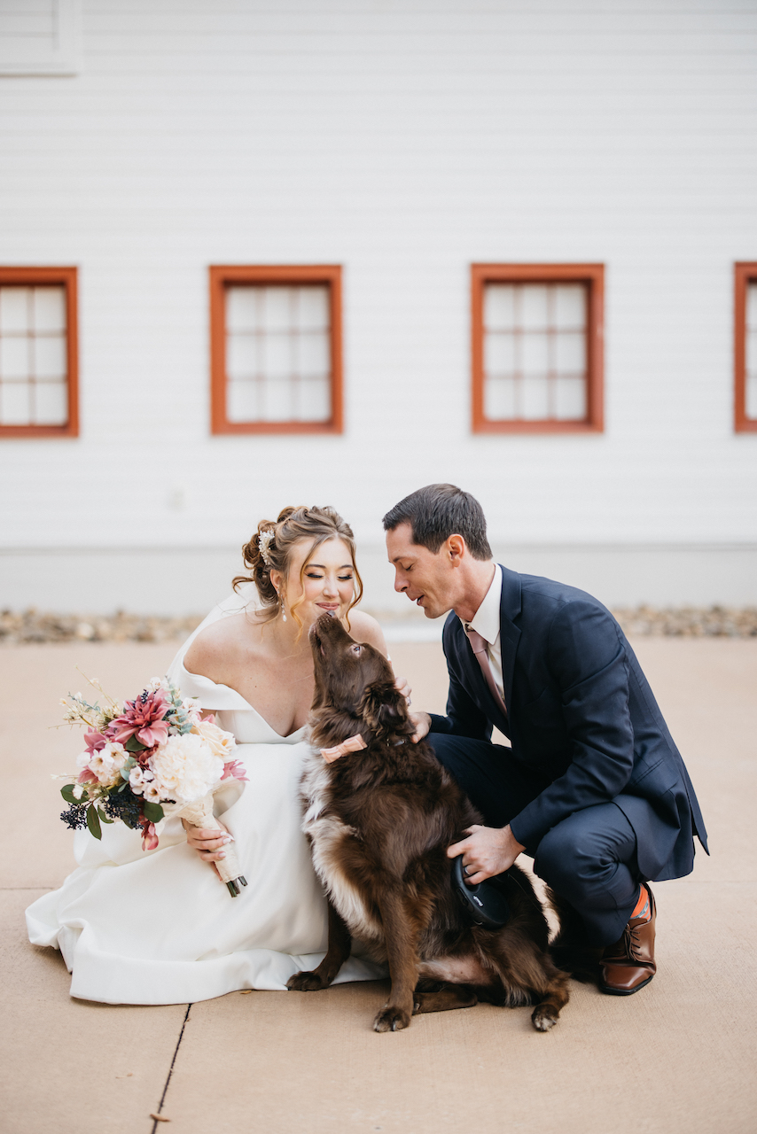 bride and groom petting dog at romantic wedding in north carolina