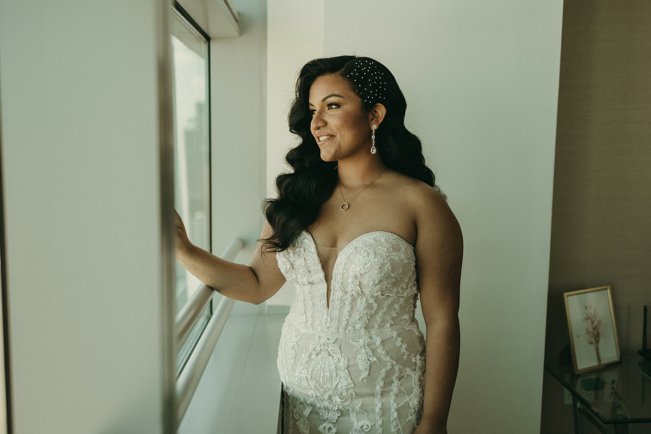 bride in wedding dress looking out a window