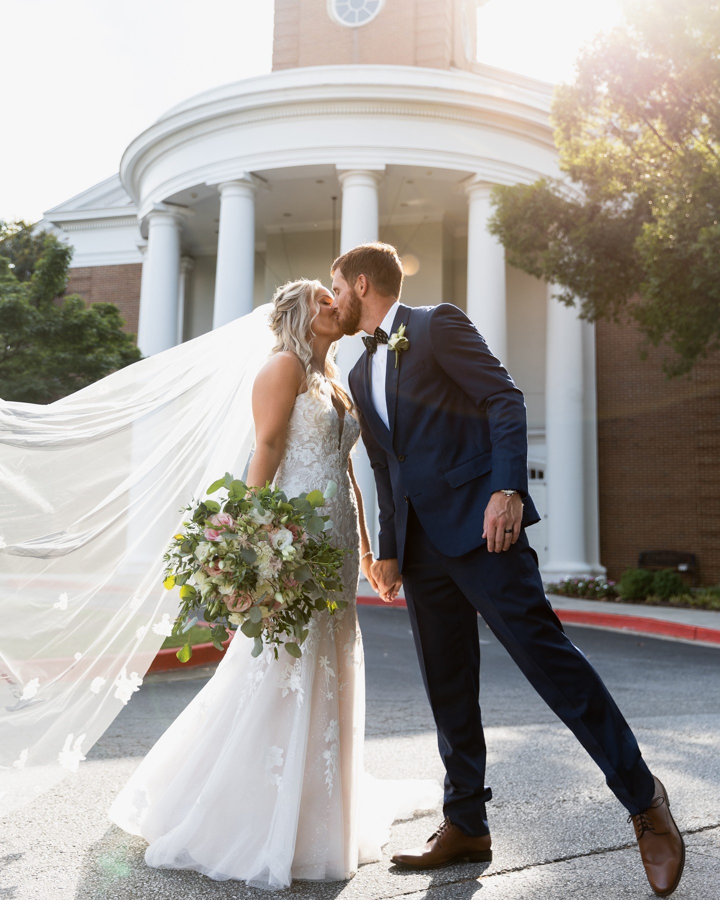 bride and groom kissing in front of wedding venue