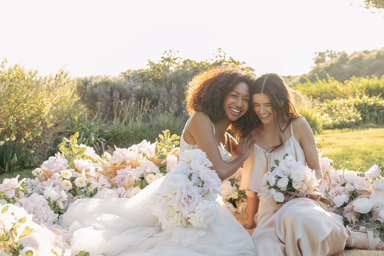 bride and bridesmaid laughing surrounded by silk wedding flowers